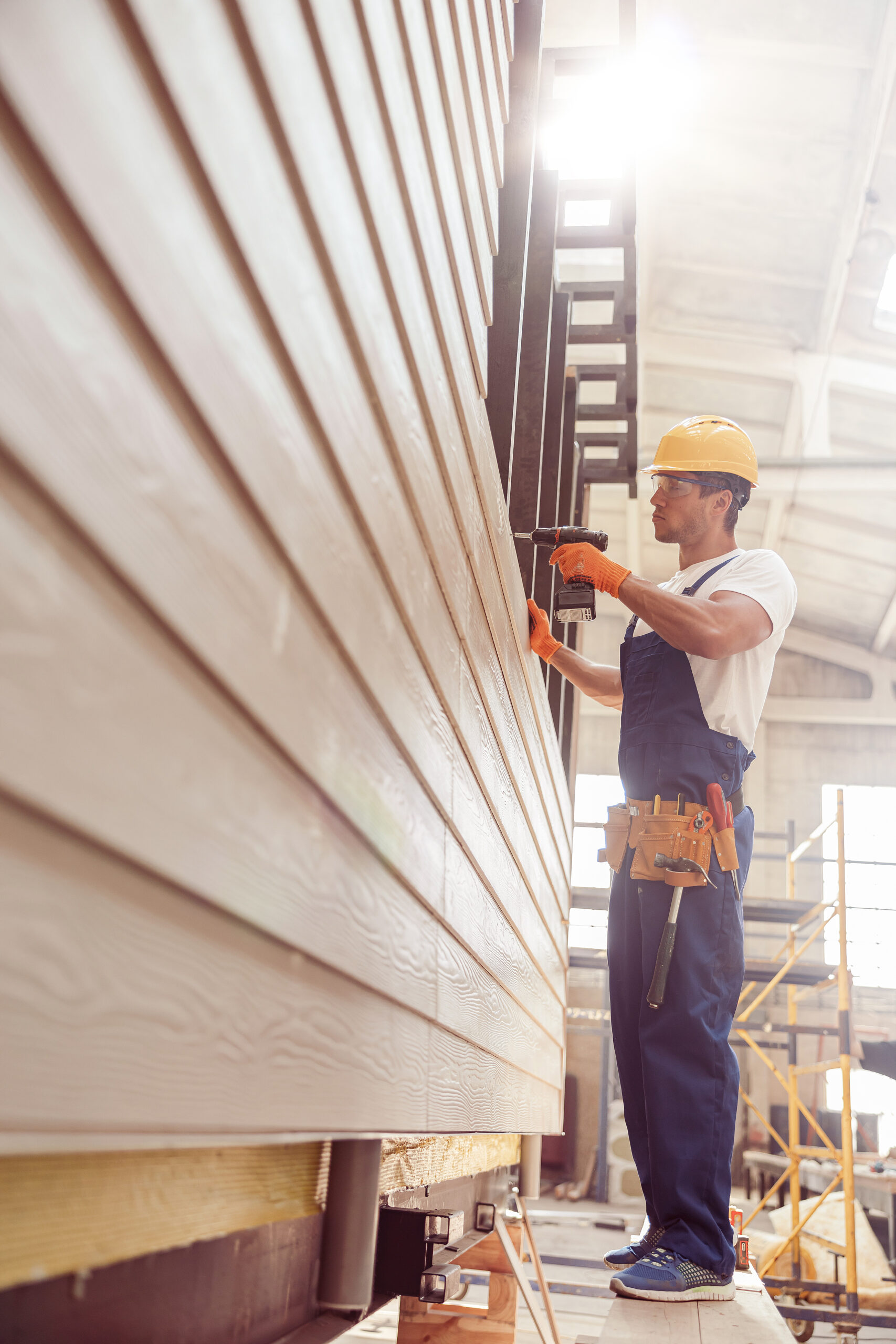 Male builder using cordless electric drill at construction site